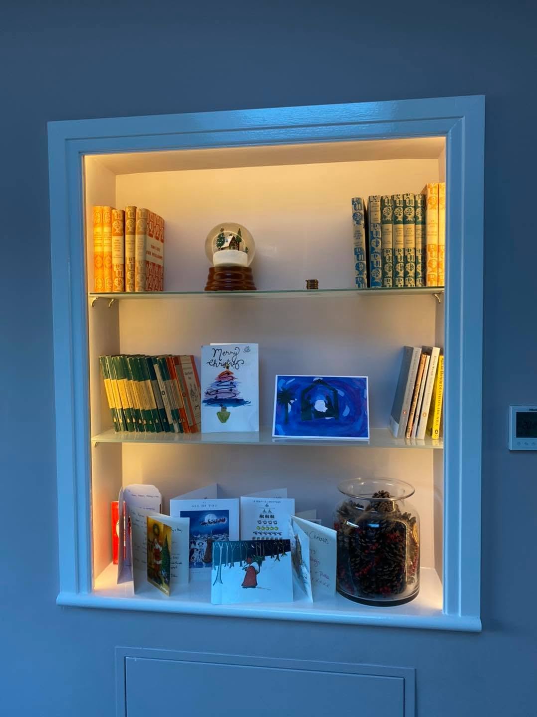 Built-in alcove shelving with warm concealed LED lighting and a navy surround